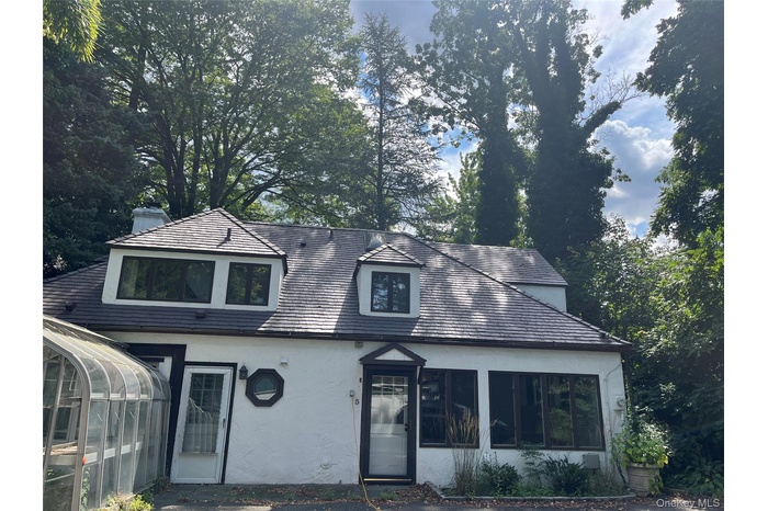View of front of home featuring stucco siding, a sunroom, and view of wooded area