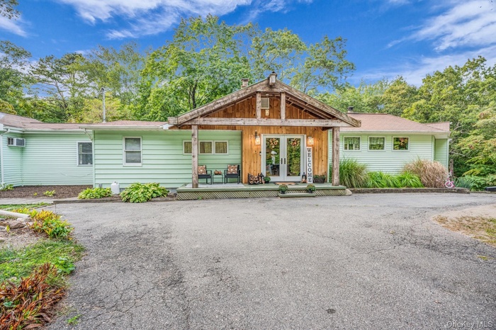 View of front of house with french doors, covered porch, and a chimney