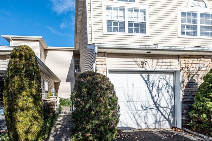 View of property exterior featuring stone siding, a gate, and an attached garage
