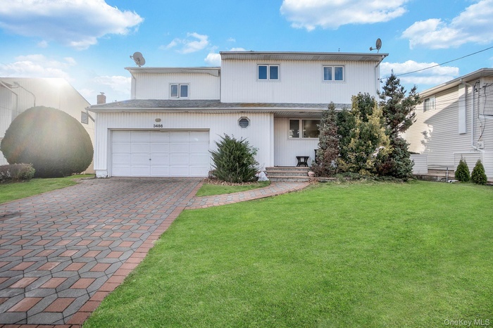 View of front facade with a front yard, decorative driveway, and a porch