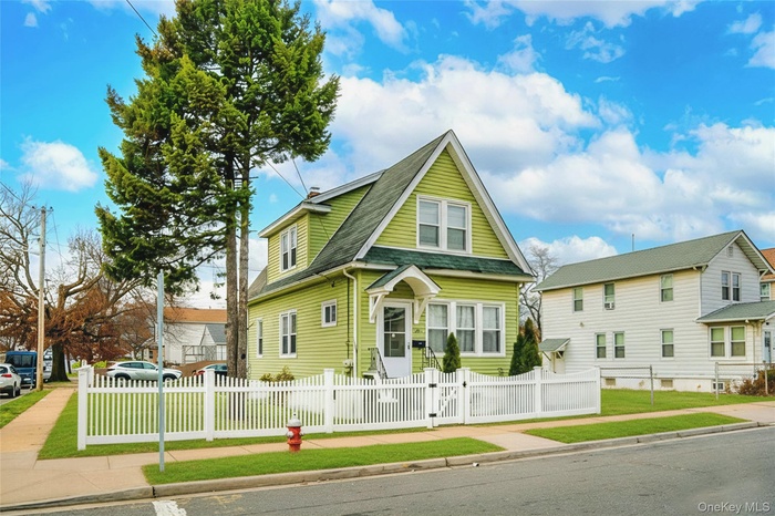 View of front of property with roof with shingles, a fenced front yard, and a gate