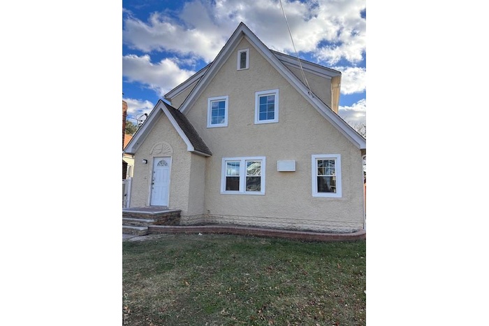 View of front of home featuring stucco siding and a front lawn