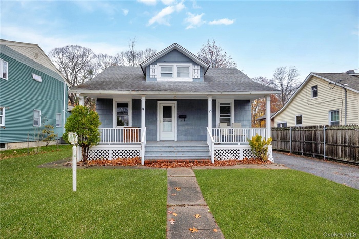 Bungalow-style house with a porch, roof with shingles, and a front yard