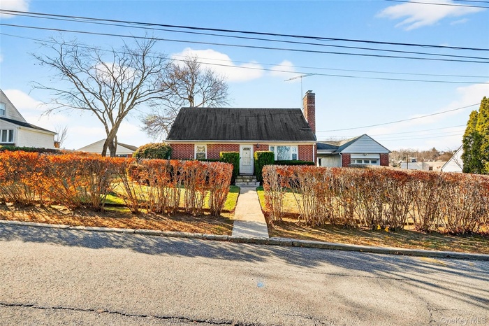 Cape cod house featuring a chimney and brick siding