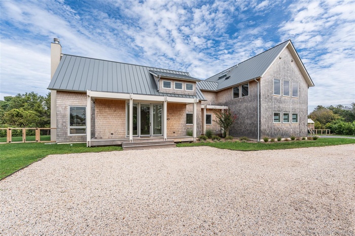 Rear view of property with a metal roof, a standing seam roof, a wooden deck, a chimney, and a yard