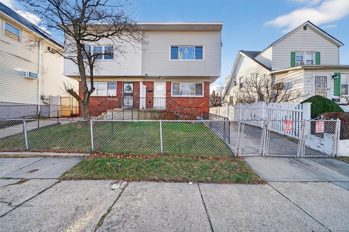 View of front of property with brick siding, a fenced front yard, and a gate