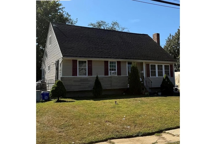 View of front facade featuring a shingled roof and a chimney