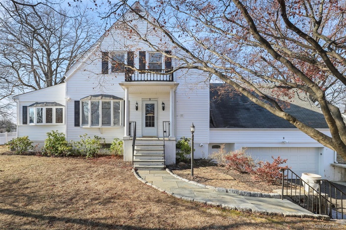 Traditional home with an attached garage, a shingled roof, and a porch