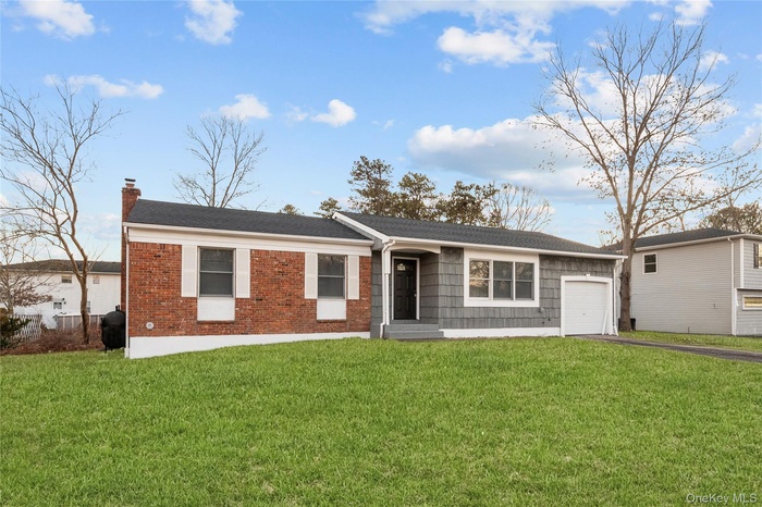 Single story home with a front yard, a chimney, a garage, brick siding, and asphalt driveway