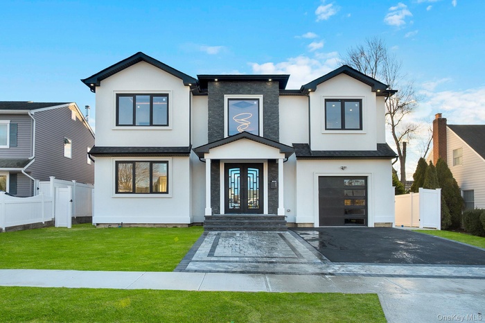 Contemporary house with stucco siding, driveway, a garage, and french doors