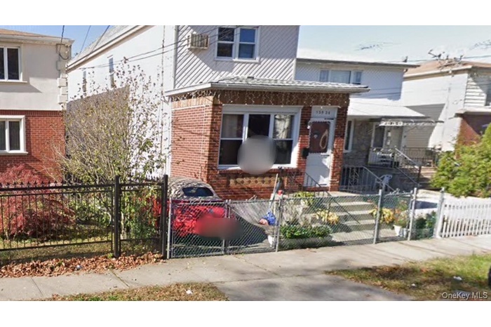View of front of property with brick siding, a fenced front yard, and a gate