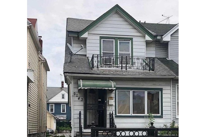 View of front of home featuring a balcony and roof with shingles