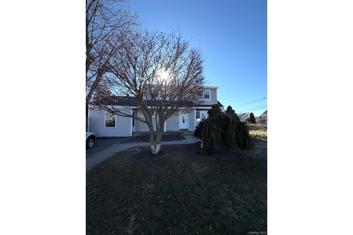 View of property hidden behind natural elements featuring a patio and a front yard