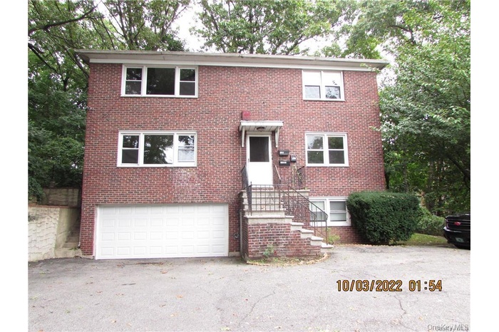 Colonial home featuring brick siding, driveway, and a garage