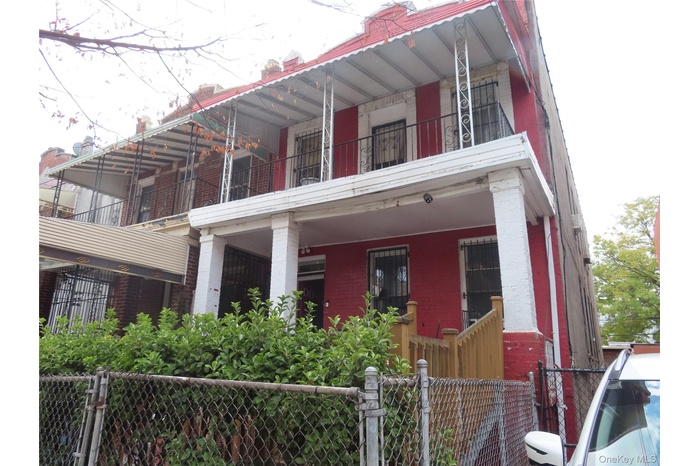 View of front facade with brick siding, a gate, a balcony, and a fenced front yard