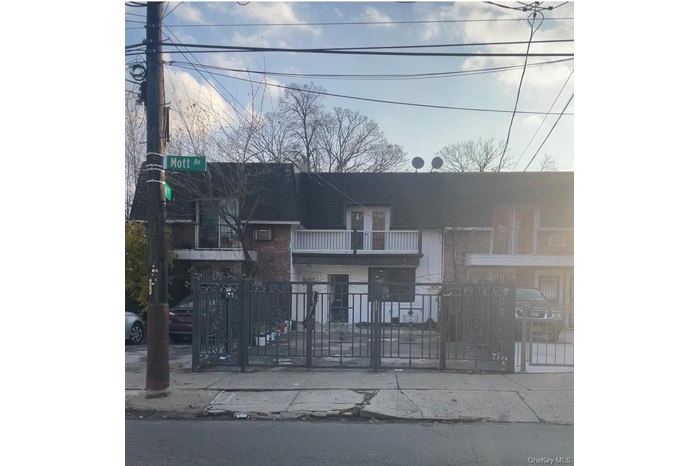 View of front facade with brick siding, a fenced front yard, a balcony, and a gate