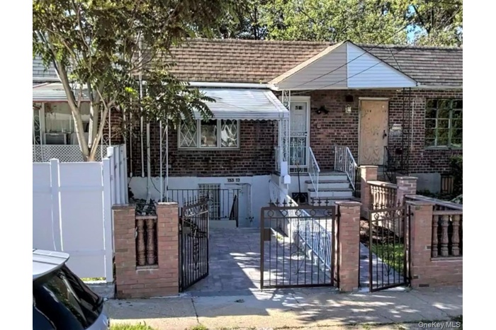 View of front of home featuring a gate, a fenced front yard, brick siding, a shingled roof, and a patio