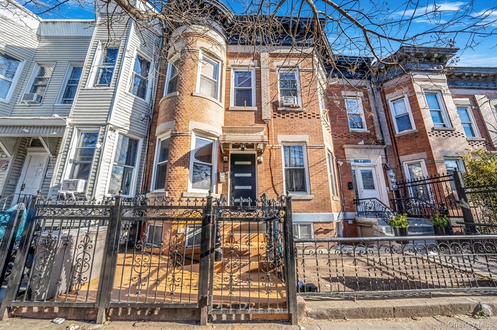 View of front of house with a gate, a fenced front yard, and brick siding