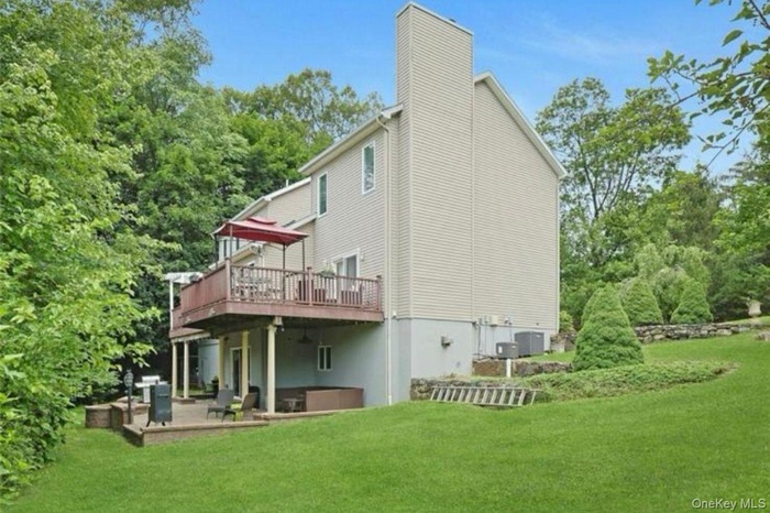 Back of property with a deck, a yard, and a chimney