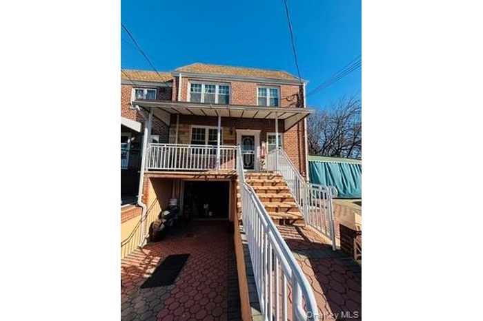 Rear view of property featuring stairway, brick siding, and a porch