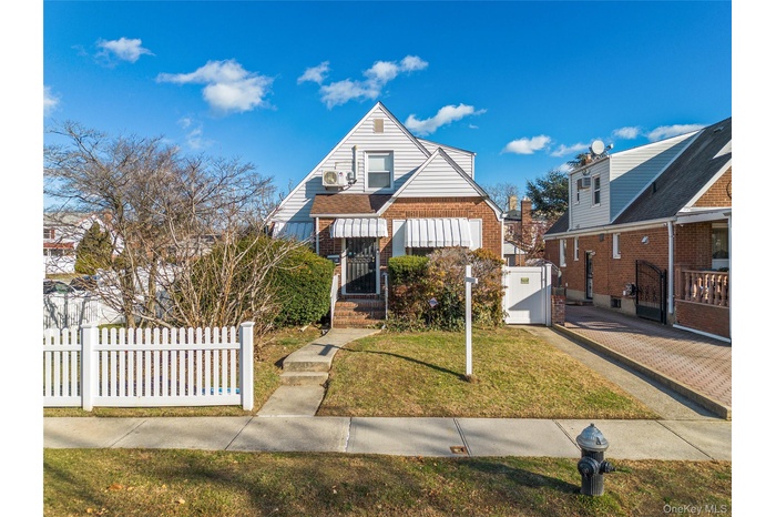 Bungalow-style home with a fenced front yard, a gate, and brick siding