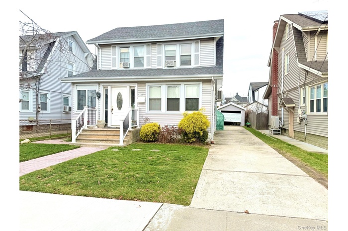 View of front facade featuring roof with shingles, an outbuilding, and concrete driveway