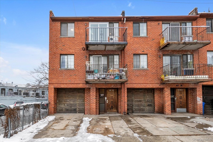 Snow covered property featuring a view of apartment building / complex, an attached garage, and driveway