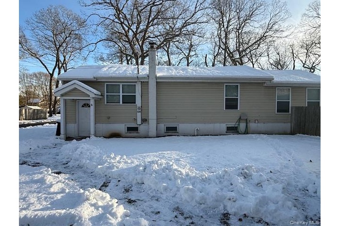Snow covered rear of property featuring a chimney