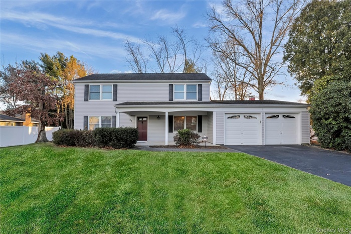 Traditional-style house featuring a porch, an attached garage, and driveway