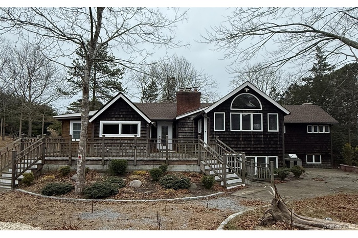 View of front of property with stairway, a chimney, roof with shingles, and a deck