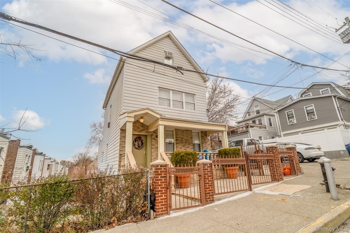 View of front facade featuring a fenced front yard, a gate, brick siding, and a residential view