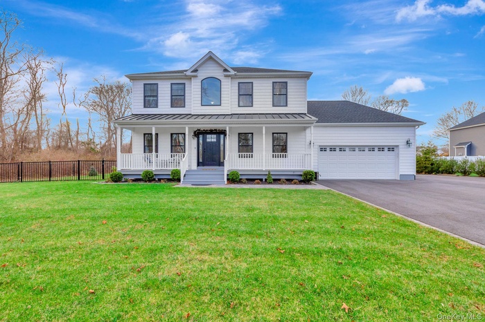 View of front facade featuring covered porch, driveway, a garage, a standing seam roof, and roof with shingles