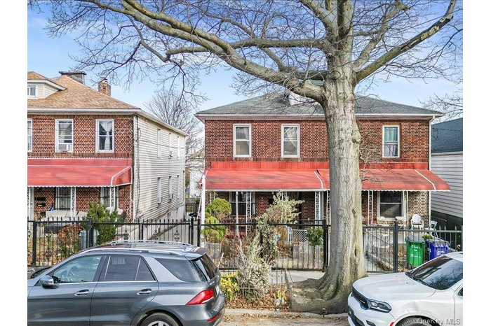 View of front facade featuring brick siding, a fenced front yard, and a shingled roof