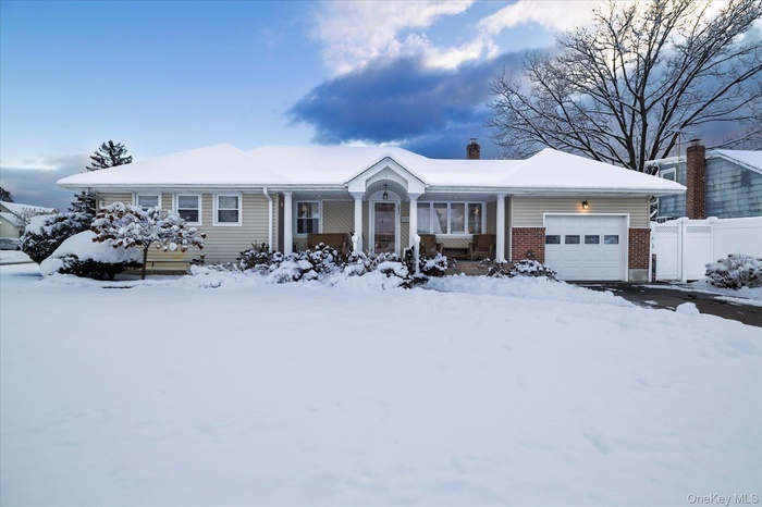 Ranch-style home with an attached garage, brick siding, a porch, and a chimney