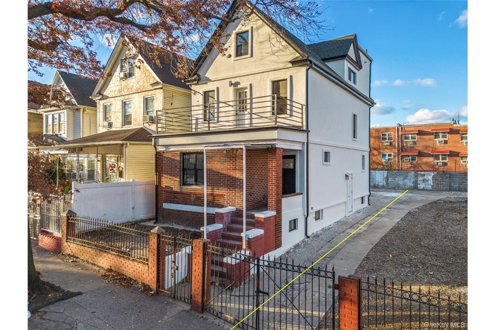 View of front of home featuring a fenced front yard, a gate, stucco siding, and a balcony