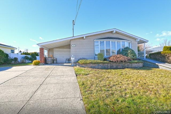 View of front of home with concrete driveway, a front lawn, and an attached garage
