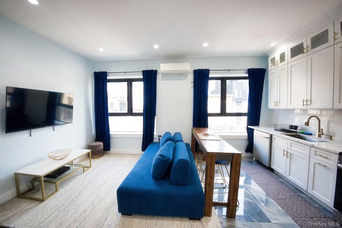 Kitchen with white cabinetry, glass insert cabinets, stainless steel appliances, recessed lighting, and an AC wall unit