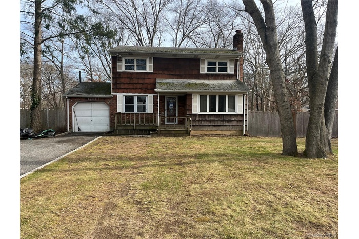 View of front of house featuring a chimney, driveway, and roof with shingles