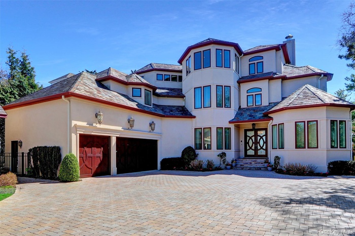 View of front of property with fence, a chimney, decorative driveway, an attached garage, and stucco siding