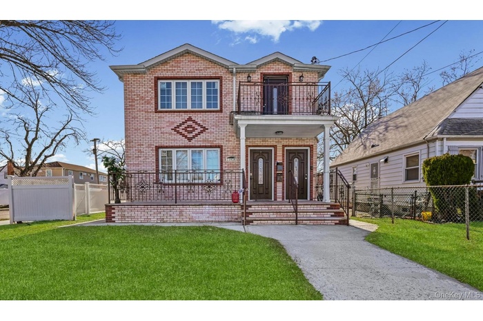 View of front of house with a balcony, a fenced front yard, and brick siding
