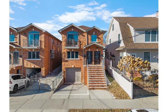 View of front of house with brick siding, a garage, concrete driveway, stairway, and a residential view