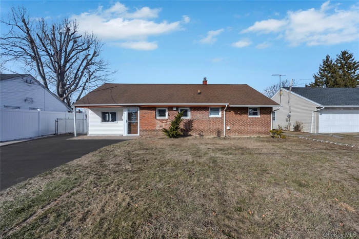 Back of property featuring roof with shingles, a chimney, and brick siding