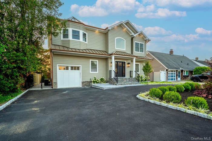 View of front facade with driveway, a standing seam roof, a metal roof, and an attached garage