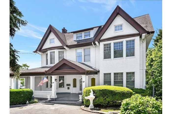 View of front of home featuring a porch, roof with shingles, and a chimney