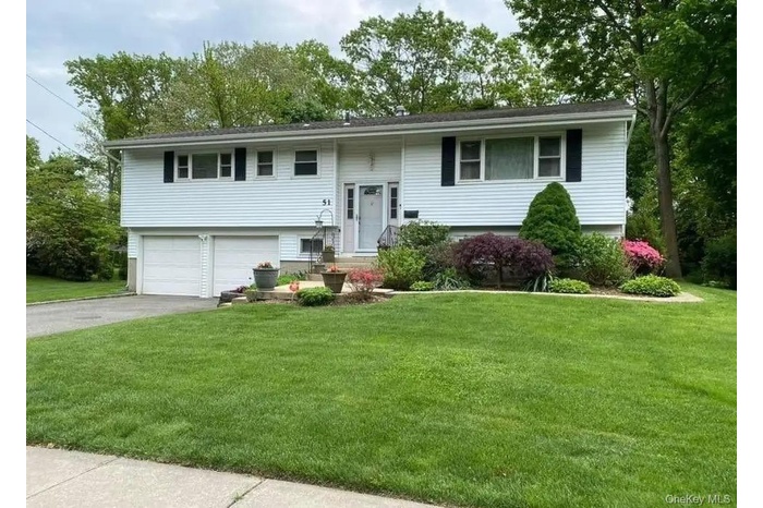 Bi-level home with a front lawn, asphalt driveway, and an attached garage