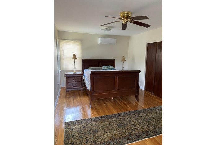 Bedroom featuring light wood-style flooring, a closet, a ceiling fan, and an AC wall unit