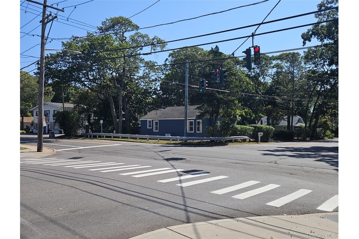 View of asphalt street with traffic lights, sidewalks, curbs, traffic signs, and street lighting