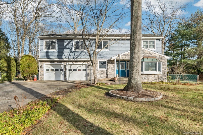 Traditional-style home with stone siding, driveway, and an attached garage