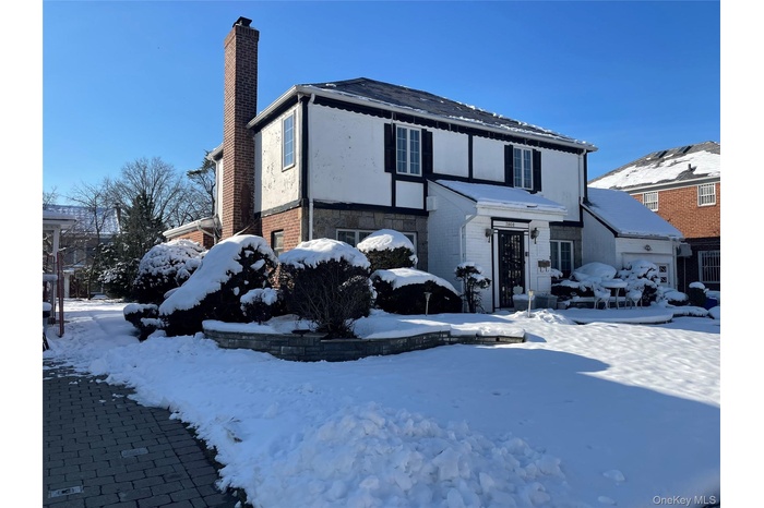English style home featuring a chimney, brick siding, and stucco siding