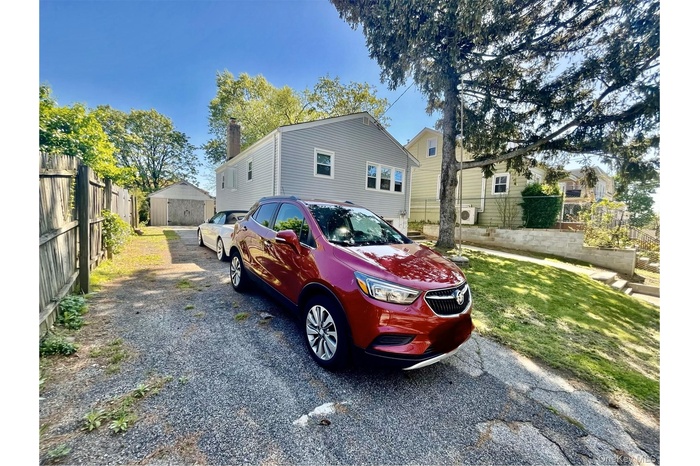 View of side of home featuring fence and gravel driveway
